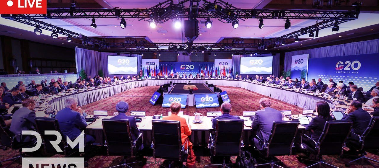 Sala ministerialna G20: okrągły stół, flagi, ekrany z napisem G20