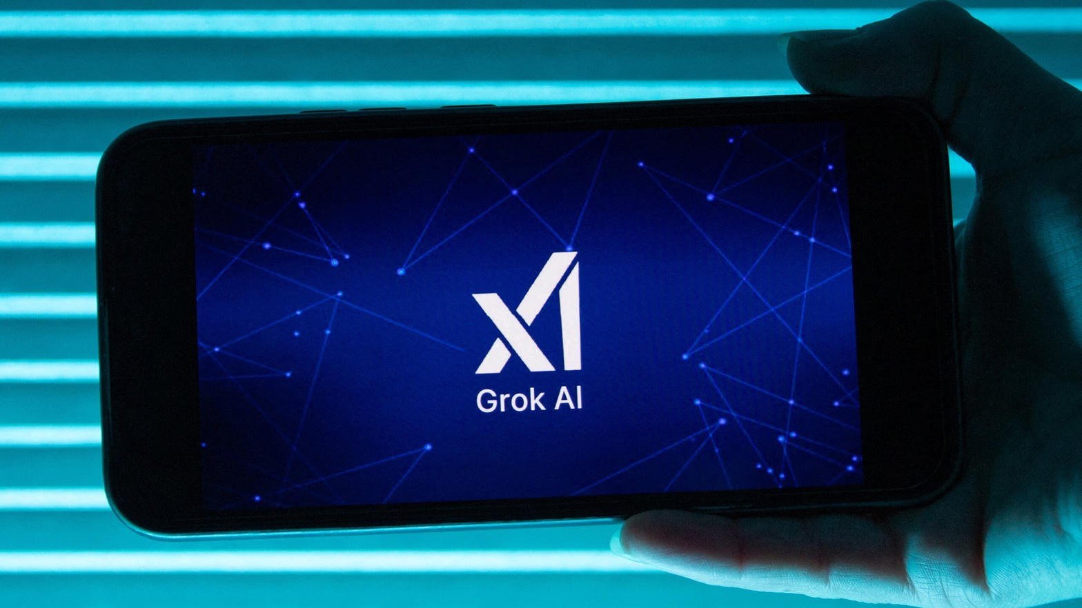 Telefon z logo xAI Grok AI na niebieskim ekranie