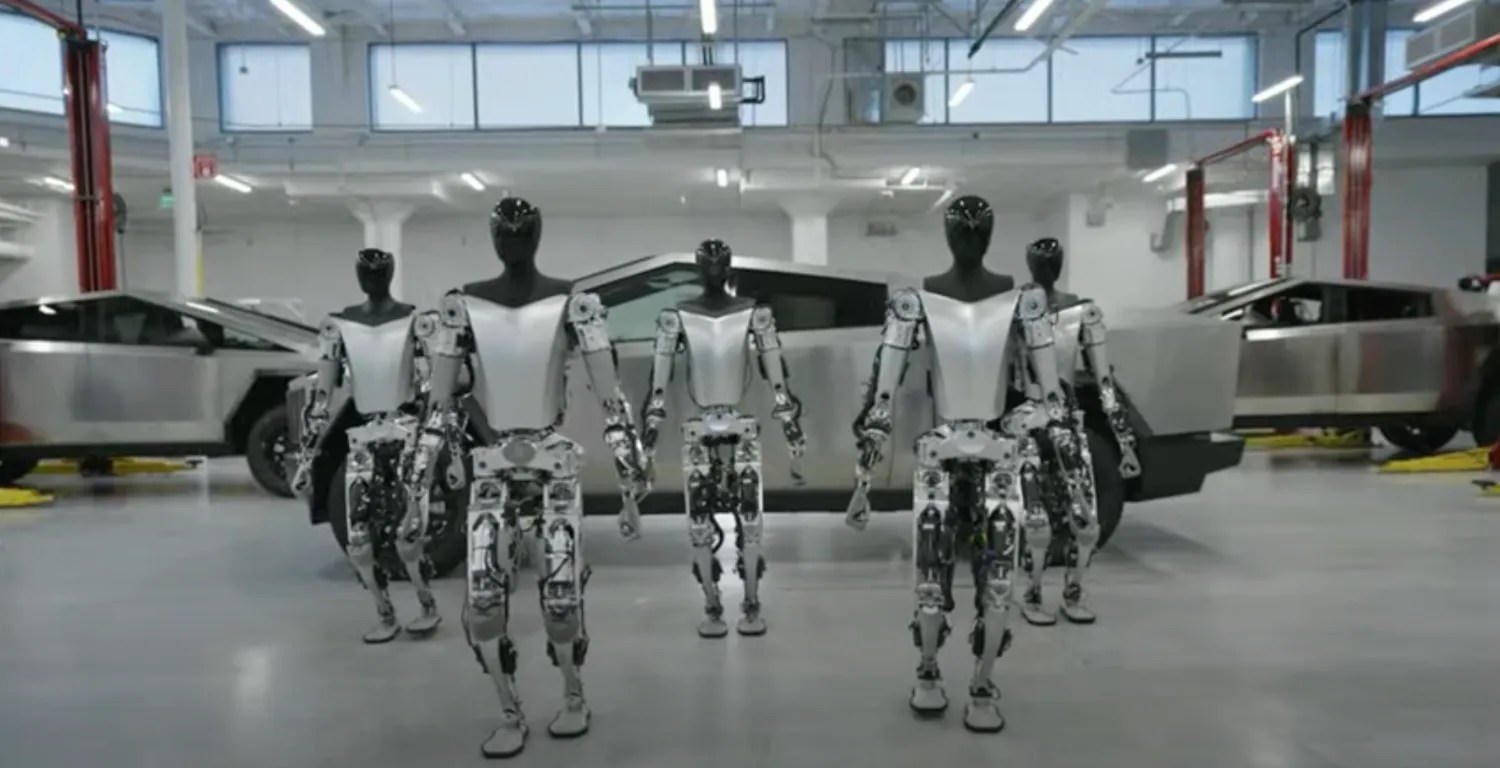 Pięć robotów Optimus przed Cybertruckami w hali Tesli