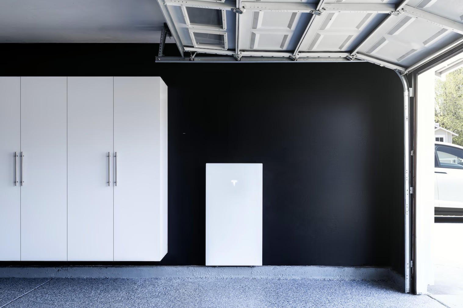 Tesla Powerwall 3 na czarnej ścianie w garażu